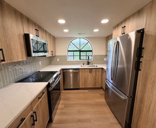A kitchen with wooden cabinets and a stainless steel refrigerator.